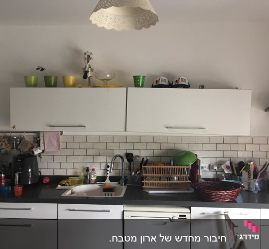 מטבח עם כלים על השיש וארונות לבנים